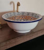 Handmade Moroccan ceramic vessel sink featuring fish scale designs and a brass rim, displayed on a wooden countertop.