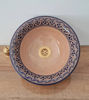 Natural terracotta ceramic bathroom sink in mid-century modern style placed on a wooden vanity counter.