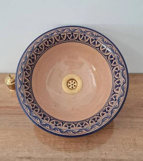 Natural terracotta ceramic bathroom sink in mid-century modern style placed on a wooden vanity counter.