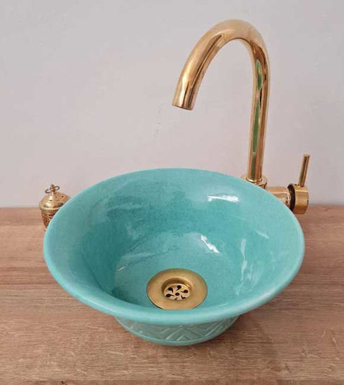 Turquoise ceramic bowl with intricate designs and a gold faucet, showcasing Moroccan craftsmanship for a stylish bathroom sink.
