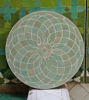 Sage green circular tile tabletop adorned with a flower design, reflecting traditional Moroccan artistry and mid-century aesthetic.