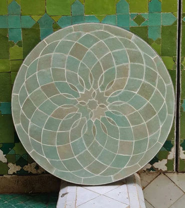 Sage green circular tile tabletop adorned with a flower design, reflecting traditional Moroccan artistry and mid-century aesthetic.