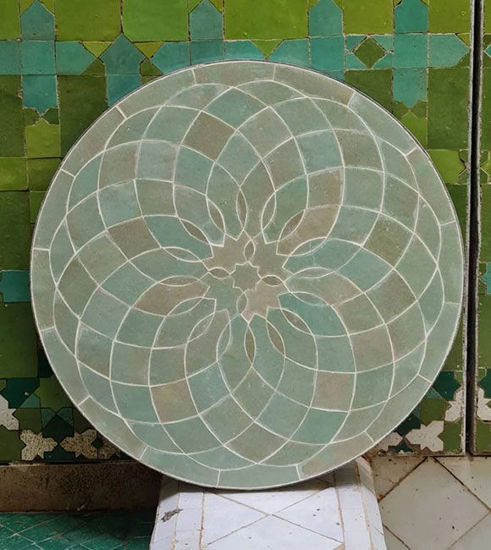 Sage green circular tile tabletop adorned with a flower design, reflecting traditional Moroccan artistry and mid-century aesthetic.