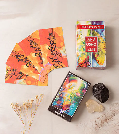 Osho Zen Tarot Deck displayed with a book, decorative rocks, and a candle, representing spiritual growth and self-awareness.
