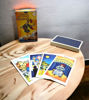 A wooden table featuring four colorful tarot cards and a Spanish guidebook from the Radiant Rider-Waite Tarot Deck.