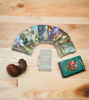 A Green Witch Tarot deck, a guidebook, and a shell arranged on a table, inviting exploration of nature's spiritual energies.