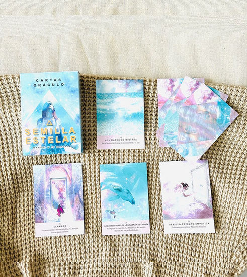 Starseed Oracle Cards in Spanish laid out on a colorful blanket, showcasing their intricate designs for spiritual guidance.