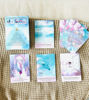 A spread of Starseed Oracle Cards in Spanish arranged on a patterned blanket, highlighting their beautiful illustrations and themes.