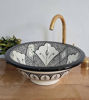Black and white ceramic vessel sink with intricate patterns, featuring a gold faucet, showcasing Moroccan craftsmanship.