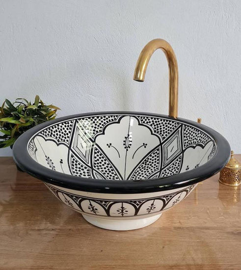 Black and white ceramic vessel sink with intricate patterns, featuring a gold faucet, showcasing Moroccan craftsmanship.