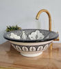 Elegant black and white washbasin with intricate designs and a gold faucet, highlighting traditional Moroccan artistry.