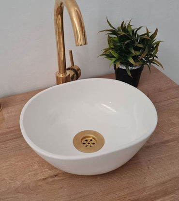 Handcrafted oval vessel sink in a white bowl with a gold faucet on a wooden counter, showcasing Moroccan artistry and design.