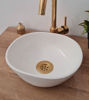 White oval vessel sink with a gold faucet on a wooden counter, highlighting intricate Moroccan craftsmanship and unique patterns.