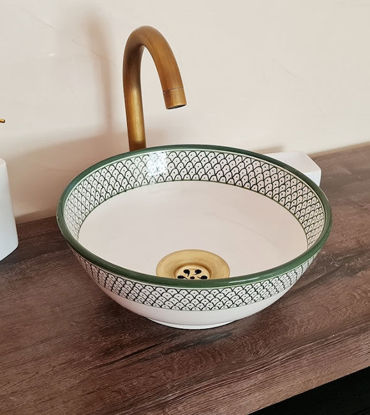 A white and green ceramic bowl with a fish scales design rests on a wooden counter, showcasing Moroccan artistry.