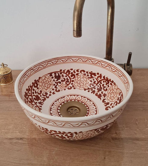Brown and white Moroccan ceramic sink with a gold faucet, showcasing intricate patterns and a Mediterranean design.