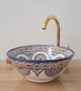 Unique Moroccan bathroom sink with a gold faucet, adorned in blue and white designs, highlighting traditional craftsmanship.