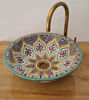 Colorful handmade Moroccan ceramic bowl with intricate patterns, paired with a brass faucet, showcasing bohemian elegance.