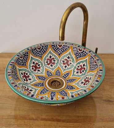 Colorful handmade Moroccan ceramic bowl with intricate patterns, paired with a brass faucet, showcasing bohemian elegance.