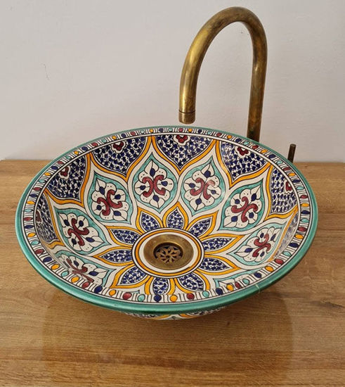 Colorful handmade Moroccan ceramic bowl with intricate patterns, paired with a brass faucet, showcasing bohemian elegance.