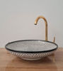 Elegant black and white ceramic sink with a gold faucet, showcasing a handcrafted fish scale pattern for a stylish bathroom accent.