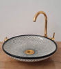 Mid-century modern ceramic sink in black and white with a gold faucet, featuring a distinctive fish scale design for artistic flair.