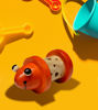Handmade wooden baby rattle featuring a small orange bug and googly eyes, designed for sensory play and motor skill development.