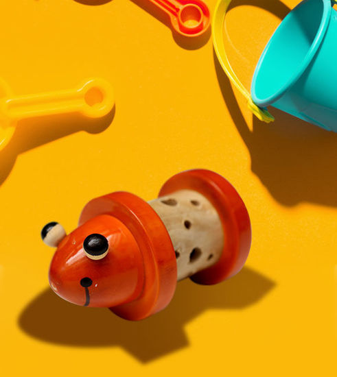 Handmade wooden baby rattle featuring a small orange bug and googly eyes, designed for sensory play and motor skill development.