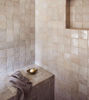 A stylish bathroom with a tiled floor and shower, showcasing handcrafted off-white Zellige tiles for added elegance.