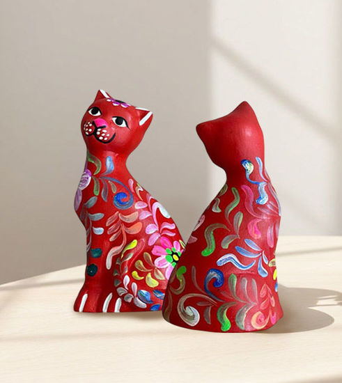 Two handmade Peruvian ceramic cats in vibrant colors sitting on a table, showcasing traditional folk art design.