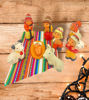 A wooden table displays a handcrafted Peruvian nativity scene ornament set, featuring the Holy Family in vibrant folk art style.